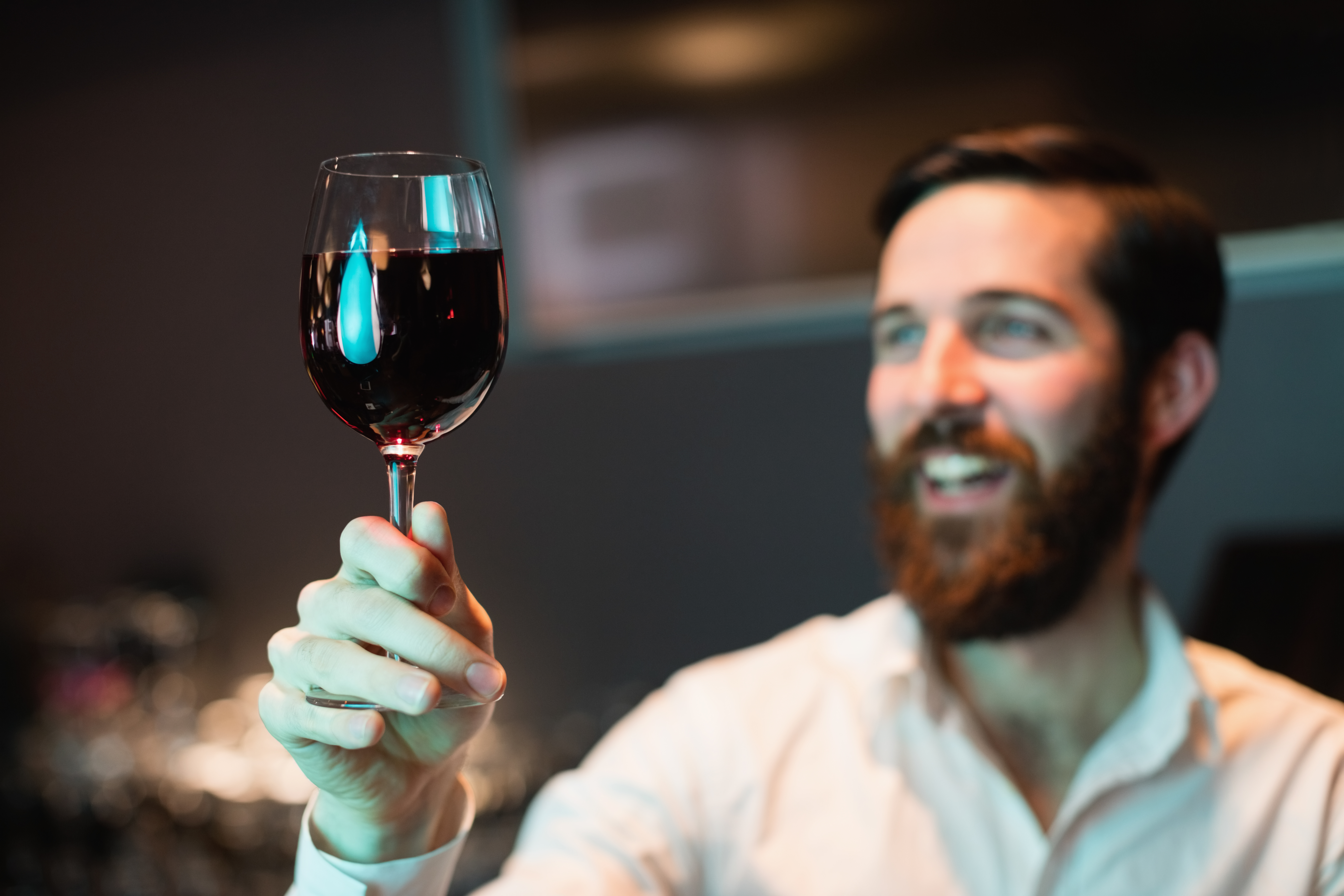 Bartender looking at glass of red wine at bar counter